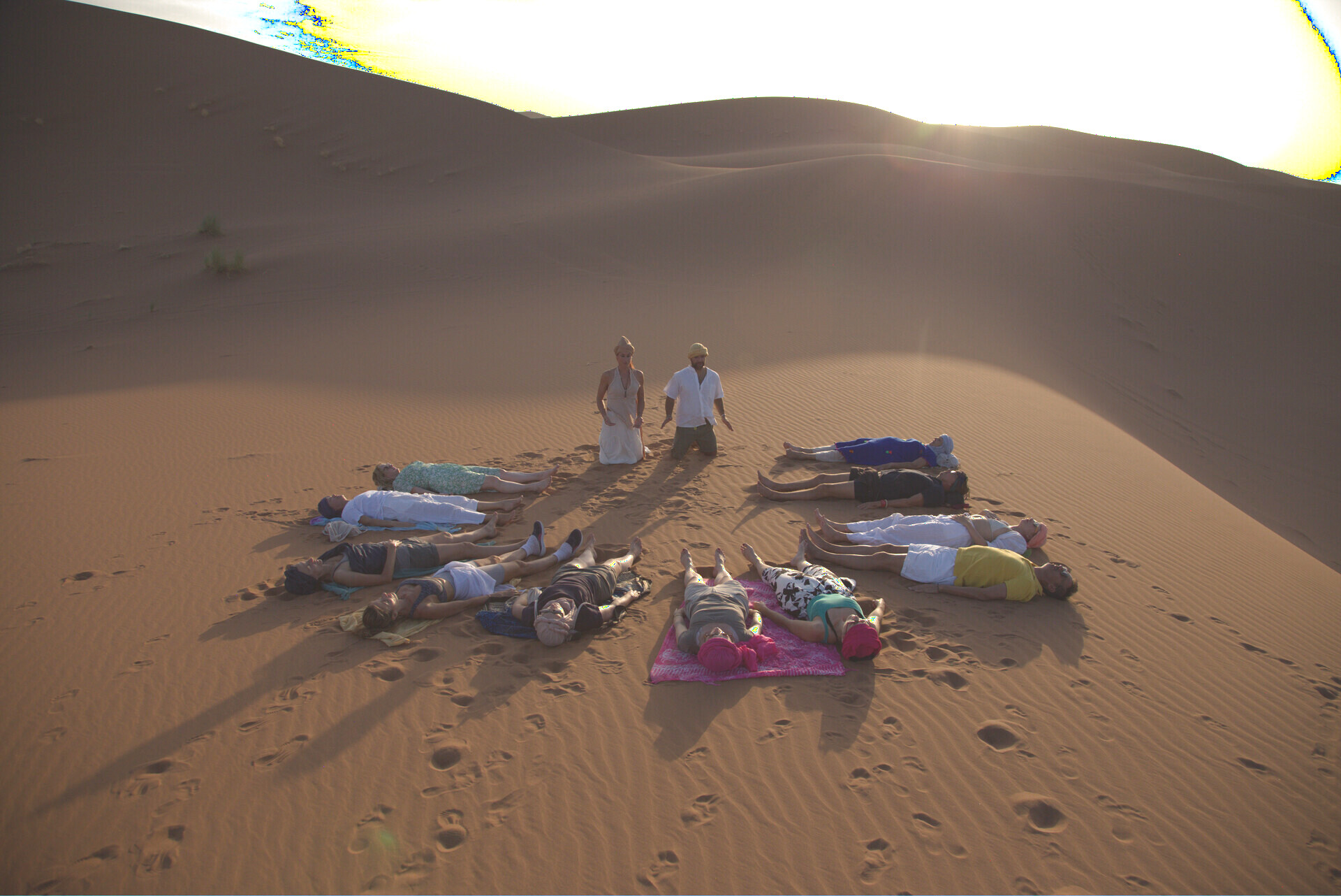 Grupo en círculo sobre las dunas de Merzouga durante una sesión de Breathwork al atardecer